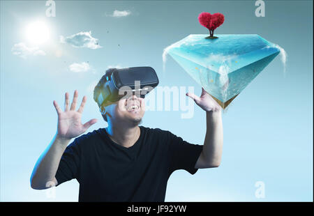 The young man wearing virtual reality goggles seen amazing diamond shape island with love shape tree   virtual imaging  . Stock Photo