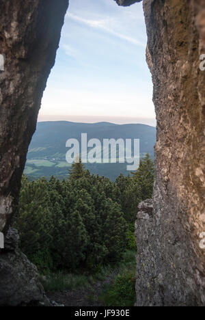 view through small natural arch on Cervena hora hill in Jeseniky mountains in Czech republic with valley with villages and Rychlebske hory mountain ra Stock Photo