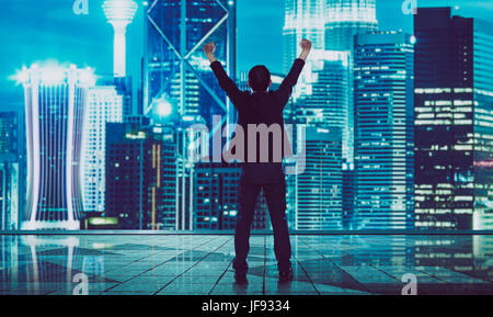 Back view of excited businessman  with arms up , blurred morden city skyline . Stock Photo