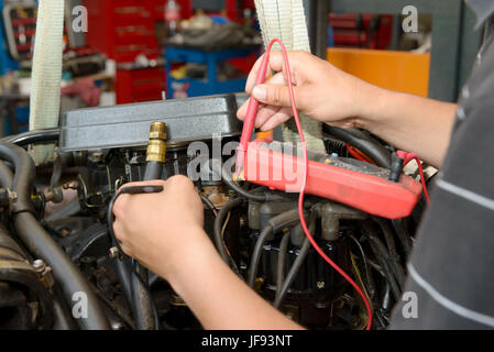 a mechanic man with digital multimeter testing ignition coil Stock Photo