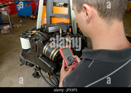 a mechanic man with digital multimeter testing ignition coil Stock Photo