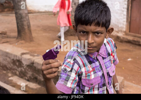 Mysore, India - October 27, 2013: Closeup of preteen boy looks threatening and pretends to kill with his purple toy gun in Mellahalli hamlet. Stock Photo