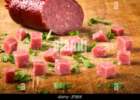 Cubes of smoked italian salami on wooden cutting board