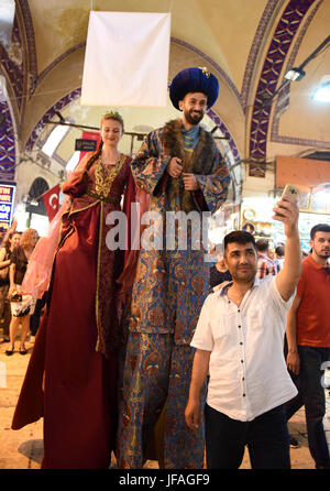 (170630) -- ISTANBUL, June 30, 2017 (Xinhua) -- A man poses for a photo with performers on stilts during a parade at the opening ceremony of Istanbul shopping festival in Istanbul, Turkey, on June 30, 2017. Istanbul on Friday marked the opening of a 15-day shopping festival at its centuries-old Grand Bazaar. (Xinhua/He Canling) Stock Photo