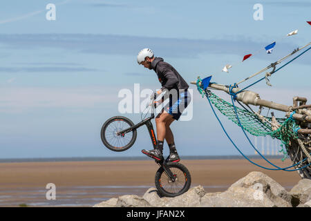 Teenager performing cycling tricks at Hoylake, Wirral.  Uk Weather. Sunny day on the west coast as beachgoers return to the sands of the resort after days of overcast and fresher weather. Today is to continue dry with some pleasantly warm sunny spells for most through the middle of the day. Stock Photo