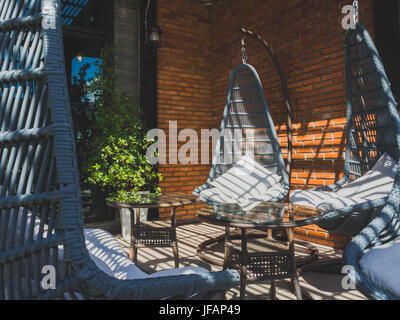 Hanging Wicker Chairs on the terrace. Stock Photo