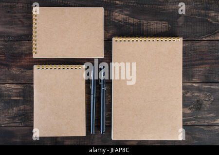 Set of three spiral notepads with two black pens on wooden table. Top view with copy space Stock Photo
