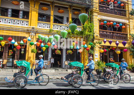 Tourists on a cyclo tour, colorful lanterns in Hoi An, Vietnam Stock Photo