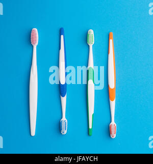 Four multicolored toothbrushes on empty blue background Stock Photo