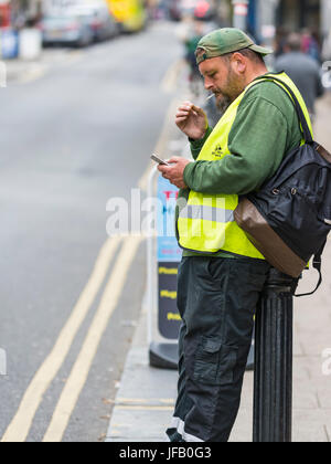 Side view of a middle aged Caucasian man smoking on the street in the UK. Stock Photo