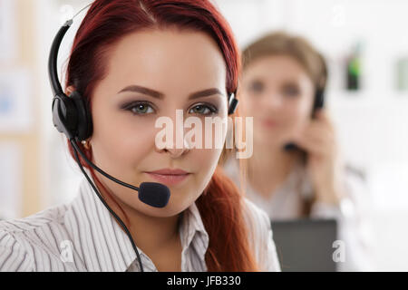 Portrait of call center worker accompanied by her team. Smiling customer support operator at work. Help and support concept Stock Photo