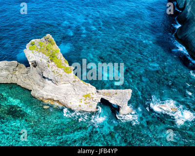 Dramatic aerial view of the coral reef surrounding the natural arch near Atuh Beach on Nusa Penida, Bali, Indonesia. Stock Photo
