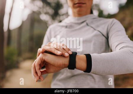 Close up of female athlete checking fitness progress on her smart watch. Woman runner using fitness app to monitor workout performance. Stock Photo
