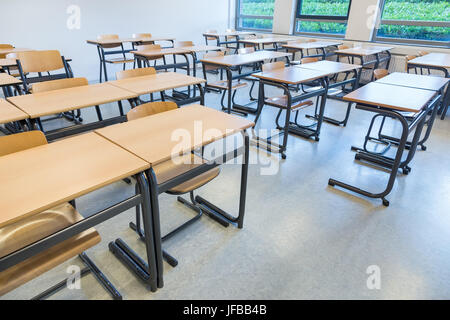Rows of tables and chairs in classroom Stock Photo