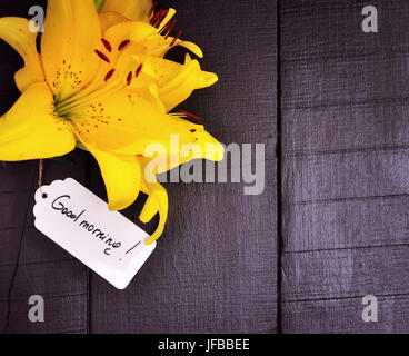 Yellow lily and a paper tag with a good morning inscription Stock Photo