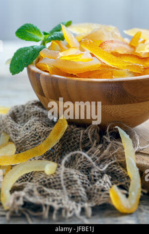 Candied citrus fruit in a wooden bowl and mint. Stock Photo