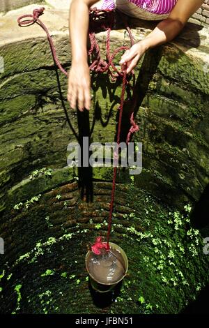 A woman pulls clean water from a water well. Stock Photo