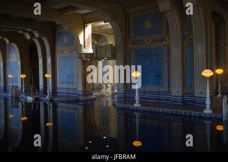 The Roman Pool at Hearst Castle, styled after an ancient Roman bath, is tiled with mosaic patterns in blue and gold, and lit with ornate lighting sculptures. Stock Photo