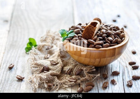 Scoop with ground coffee in a wooden bowl with coffee beans. Stock Photo