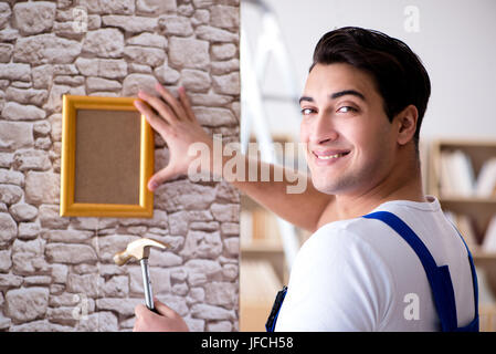 Repairman putting picture frame onto wall Stock Photo