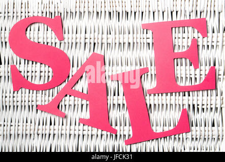 Pink red sale letters cut from cardboard paper on a white wicker texture background. Special offer campaign and promotion banner for marketing. Stock Photo