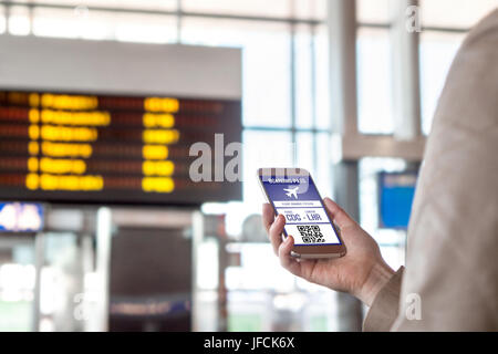 Boarding pass in smartphone. Woman holding phone in airport with mobile ticket on sceen. Modern travelling technology and easy access to aeroplane. Stock Photo