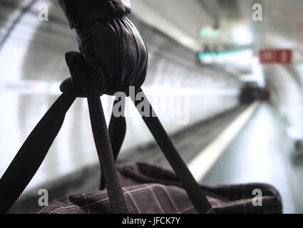 Close up of terrorist holding black bag in hand, possibly timebomb. Man planning a dangerous explosion in subway. Terrorism in underground metro. Stock Photo