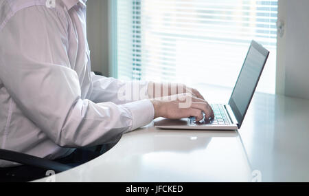 Office worker or entrepreneur typing and writing with notebook laptop in workplace. Start up businessman responding to email or commenting. Stock Photo