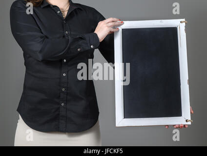 Woman holding vertical chalkboard on a dark gray background. Free blank empty copy space for text, menu or specials. Waitress in a restaurant. Stock Photo
