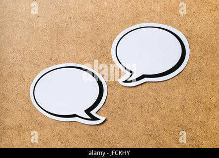 2 blank speech bubbles on a light brown wooden cork board background. Chat bubble cut from paper and cardboard. Discussion, chat and commenting concep Stock Photo