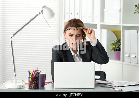 Portrait of surprised businesswoman looking at laptop screen. Impressed woman putting off her glassed. Shocking, unexpected, breaking news, problems,  Stock Photo