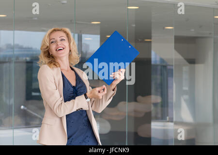 Happy excited business woman celebrating and dancing in her office Stock Photo