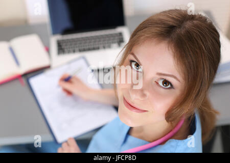 Portrait of female medicine therapeutist doctor working at her office. Woman fills documentation at her working place. High angle view. Stock Photo