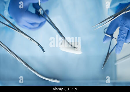 Close up view of doctor hands holding surgical tools. Group of surgeons operating patient in surgical theatre. Surgery and emergency concept Stock Photo
