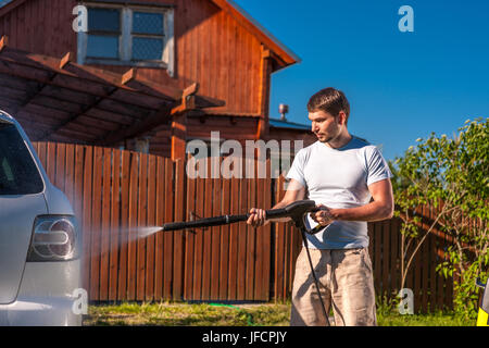Man washing car in front of house Stock Photo