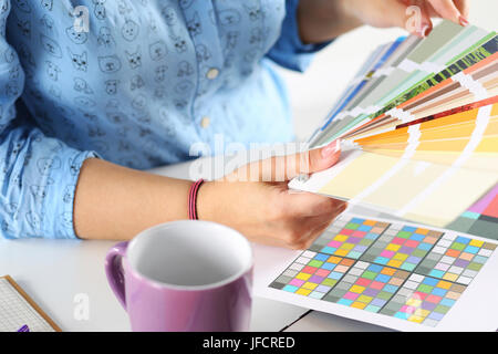 Hands of female designer in office working with colour samples. Woman at workplace choosing colourful paper charts. Creative people or advertising bus Stock Photo