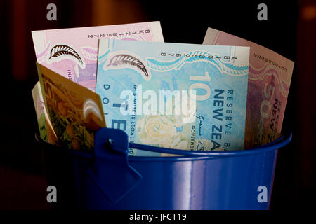 New Zealand dollars in a blue bucket Stock Photo