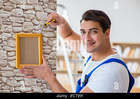 Repairman putting picture frame onto wall Stock Photo