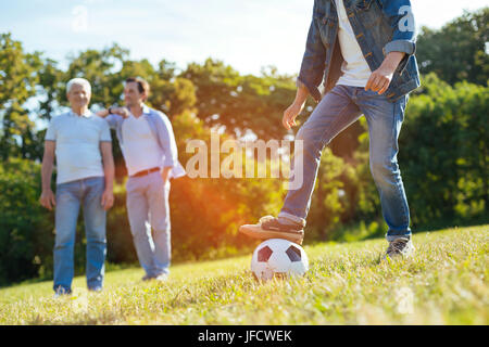 Like father like son. Caring smart nice gentleman inviting his father joying him and his son while enjoying football game in the park Stock Photo