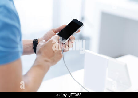 Neet to check it action. Close up look on a customer trying out a mockup gadget while shopping for a new cellphone at an electronics store. Stock Photo