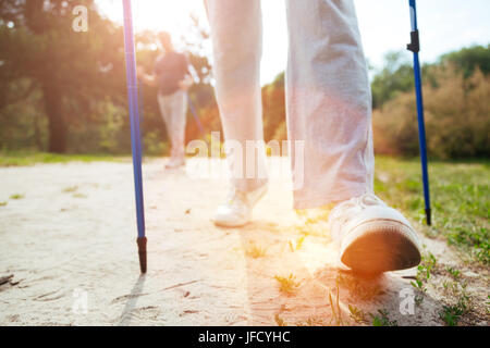 Movement is life. Nice active aged man holding walking poles and making a step forward while practicing sport activities Stock Photo