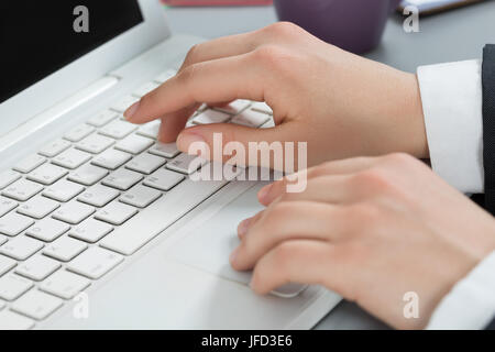 Close-up of woman's hands typing something at laptop. Woman working at the office. Stock Photo