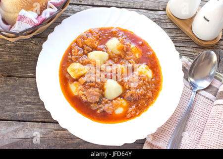 Hungarian goulash soup in plate on wooden table Stock Photo