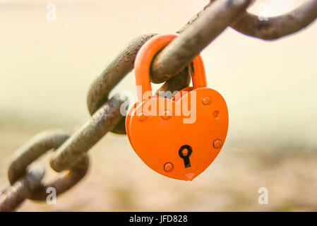Padlock in a shape of heart locked on a chain. Stock Photo