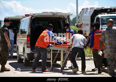 Members of the provincial Disaster Risk Reduction Management Office transport a volunteer with simulated leg injuries to an ambulance during a Pacific Angel 2017 mass casualty response exercise at Bogo City Hall, Northern Cebu Province, Philippines, June 25, 2017. As part of PACANGEL 2017, local first responders worked together with U.S. and Philippine forces to share and teach best practices in public health, mass casualty response and other related topics. (U.S. Air Force photo by Tech. Sgt. Jeff Andrejcik) Stock Photo