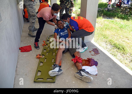 Members of the provincial Disaster Risk Reduction Management Office place a volunteer with a simulated leg injury on a long spine board during a mass casualty response exercise at Bogo City Hall, Northern Cebu Province, Philippines, June 25, 2017. As part of Pacific Angel 2017, local first responders worked together with U.S. and Philippine forces to share and teach best practices in public health, mass casualty response and other relevant topics. (U.S. Air Force photo/Tech. Sgt. Jeff Andrejcik) Stock Photo