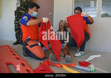 Members of the provincial Disaster Risk Reduction Management Office treat a volunteer with a simulated leg injury during a mass casualty response exercise during Pacific Angel 2017 at Bogo City Hall, Northern Cebu Province, Philippines, June 25, 2017. As part of PACANGEL 2017, local first responders worked together with U.S. and Philippine forces to share and teach best practices in public health, mass casualty response and other related topics. (U.S. Air Force photo by Tech. Sgt. Jeff Andrejcik) Stock Photo