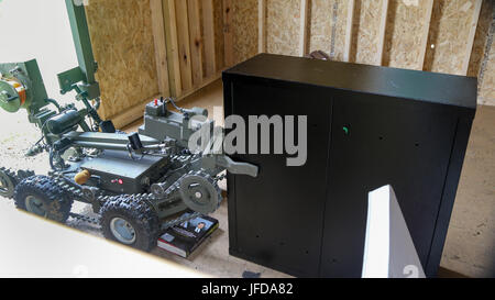 A Mini ANDROS II Robot, controlled by personnel assigned to Rapides Parish Sheriff’s Office, La., working together with Soldiers assigned to 705th EOD Company, 63rd EOD Battalion, 52nd EOD Group, 20th CBRNE Command, to move a safe containing explosives during Raven’s Challenge 2017 at Camp Shelby, Miss., June 29, 2017. Raven’s Challenge is an annual training event that provides Explosive Ordnance Disposal personnel and Public Safety Bomb Squads of both military and government agencies interoperability in a realistic domestic tactical environment. (U.S. Army photo by Sgt. Ashley Marble, 55th Si Stock Photo