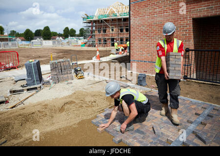Barratt Homes development construction site labourers lay a block paving drive in Walkden Salford nr Manchester. Stock Photo