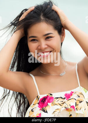 Portrait of young beautiful asian woman smiling and walking outside. Girl touching her hair. Summer time, relaxation or vacations concept Stock Photo